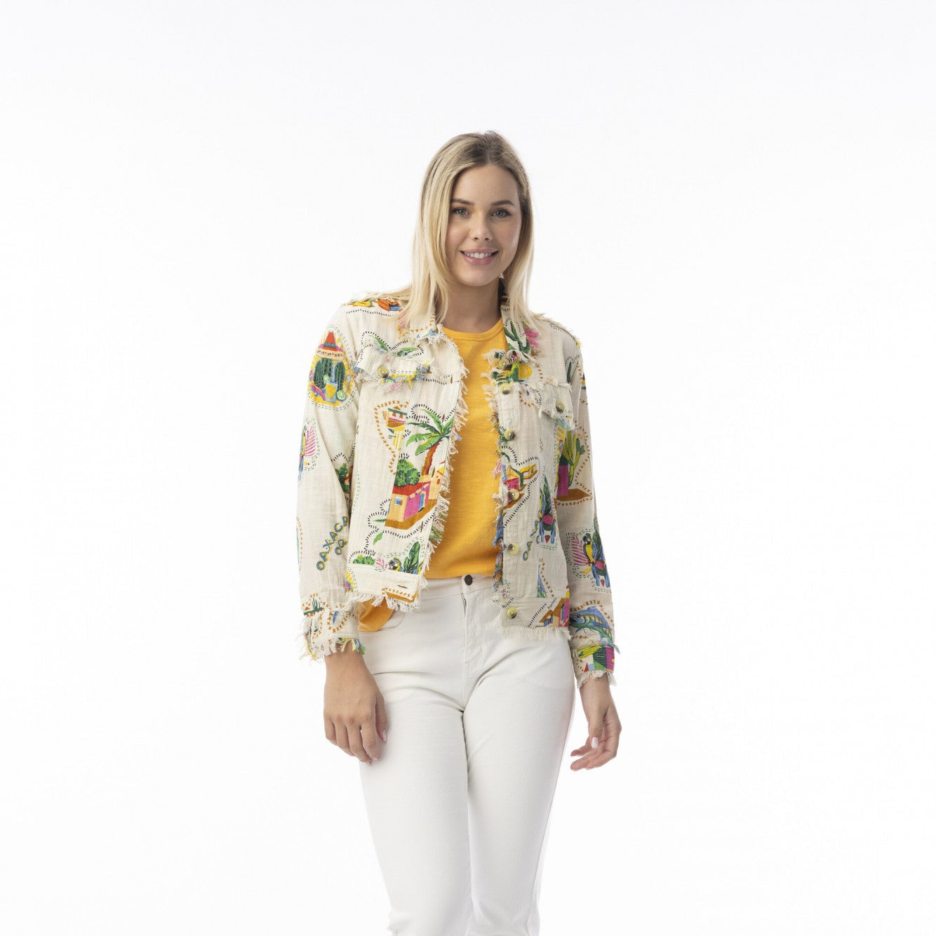 Woman wearing a colorful guatemala print jacket, yellow top, and white pants on a white background