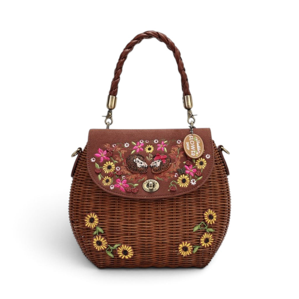 The Happy Shoe Shop Vendula London amber wicker basket bag with sunflower embroidery and hedgehog appliqué details.
