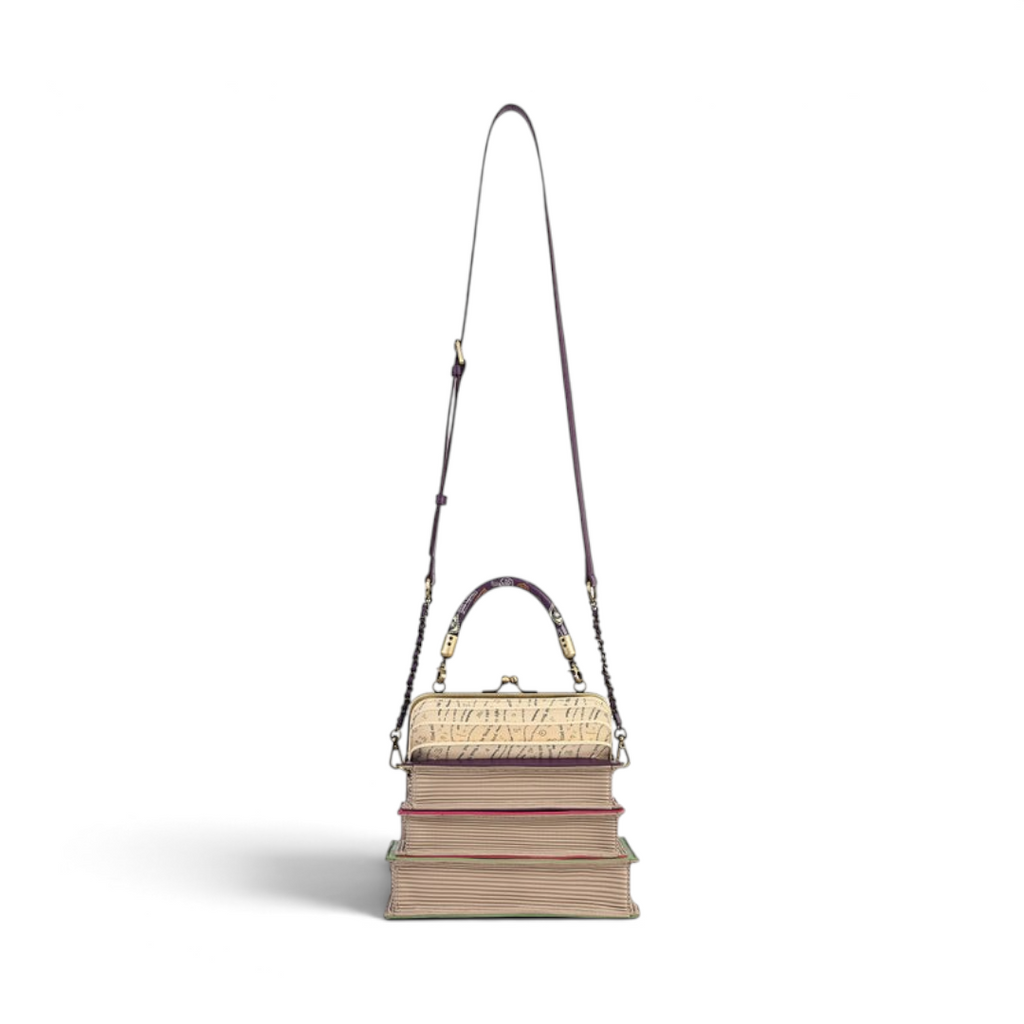 The Happy Shoe Shop Vendula London book stack handbag in vegan leather with a clip-frame opening and crossbody strap.