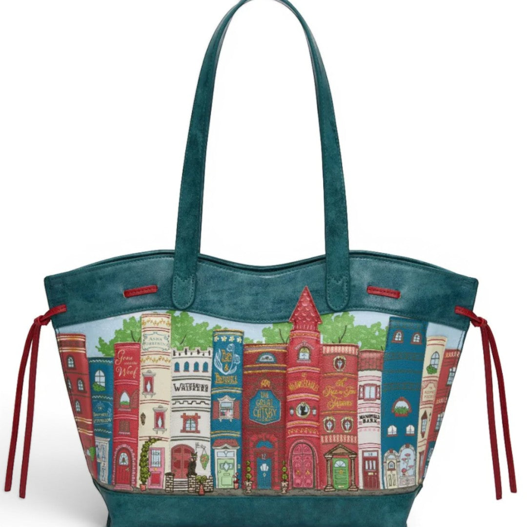 The Happy Shoe Shop Stella Tote features a bookshelf design with book spines and building facades in vibrant colors. Teal vegan leather.