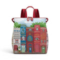 The Happy Shoe Shop Bookshelf Boulevard Tessa Backpack, a vegan leather backpack with a whimsical book spine design, red straps, and a sky background.