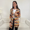 The Happy Shoe Shop Cinnamon Creations knitted hooded cardigan with a vibrant autumnal maple leaf geometric pattern.