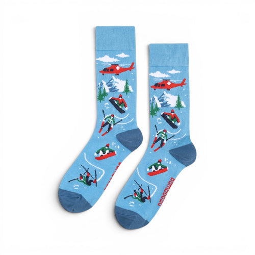 The Happy Shoe Shop Men's Snow Escape bamboo socks in sky blue with skiers, snowboarders, helicopters, and mountains.