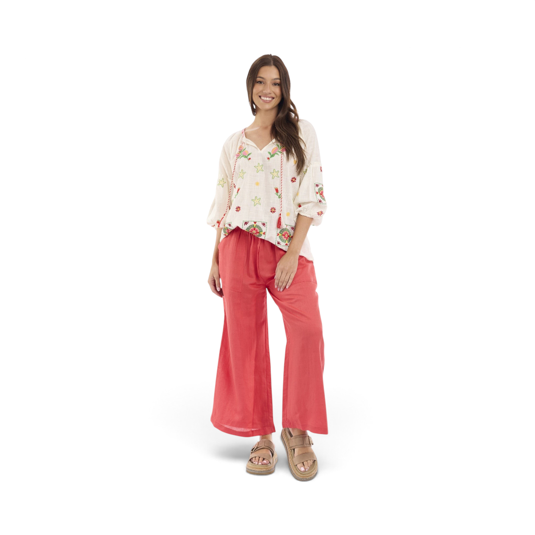 Model wearing The Happy Shoe Shop Orientique Escape Maya Top, a cream organic cotton blouse with floral embroidery.