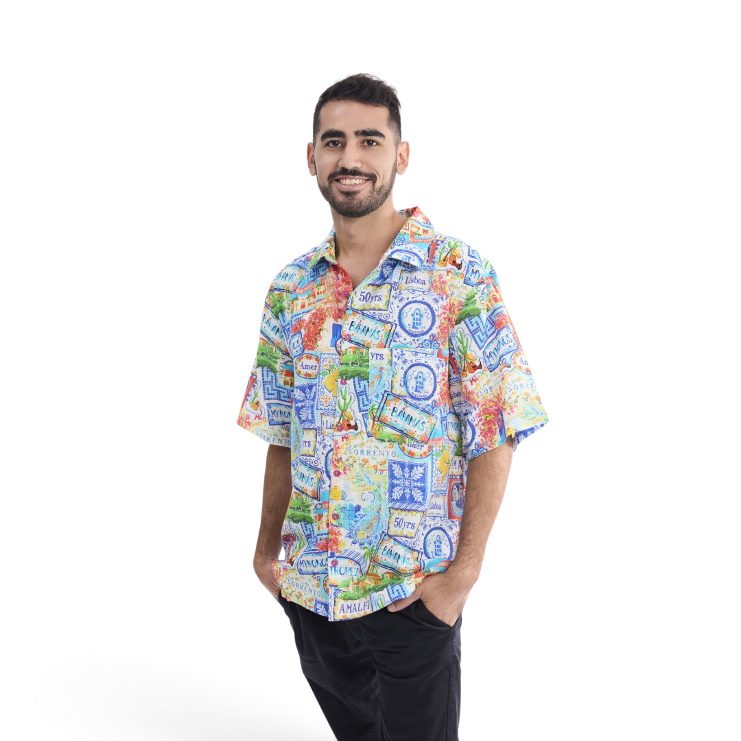 A man wearing a The Happy Shoe Shop short sleeve organic cotton shirt with a colourful patchwork travel print.