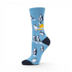 The Happy Shoe Shop unisex blue bamboo socks with a pattern of penguins and a sunset.