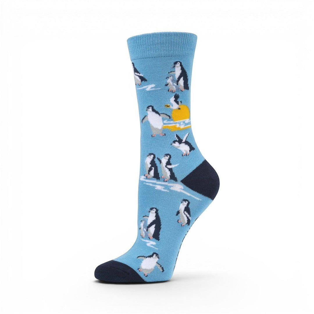The Happy Shoe Shop unisex blue bamboo socks with a pattern of penguins and a sunset.