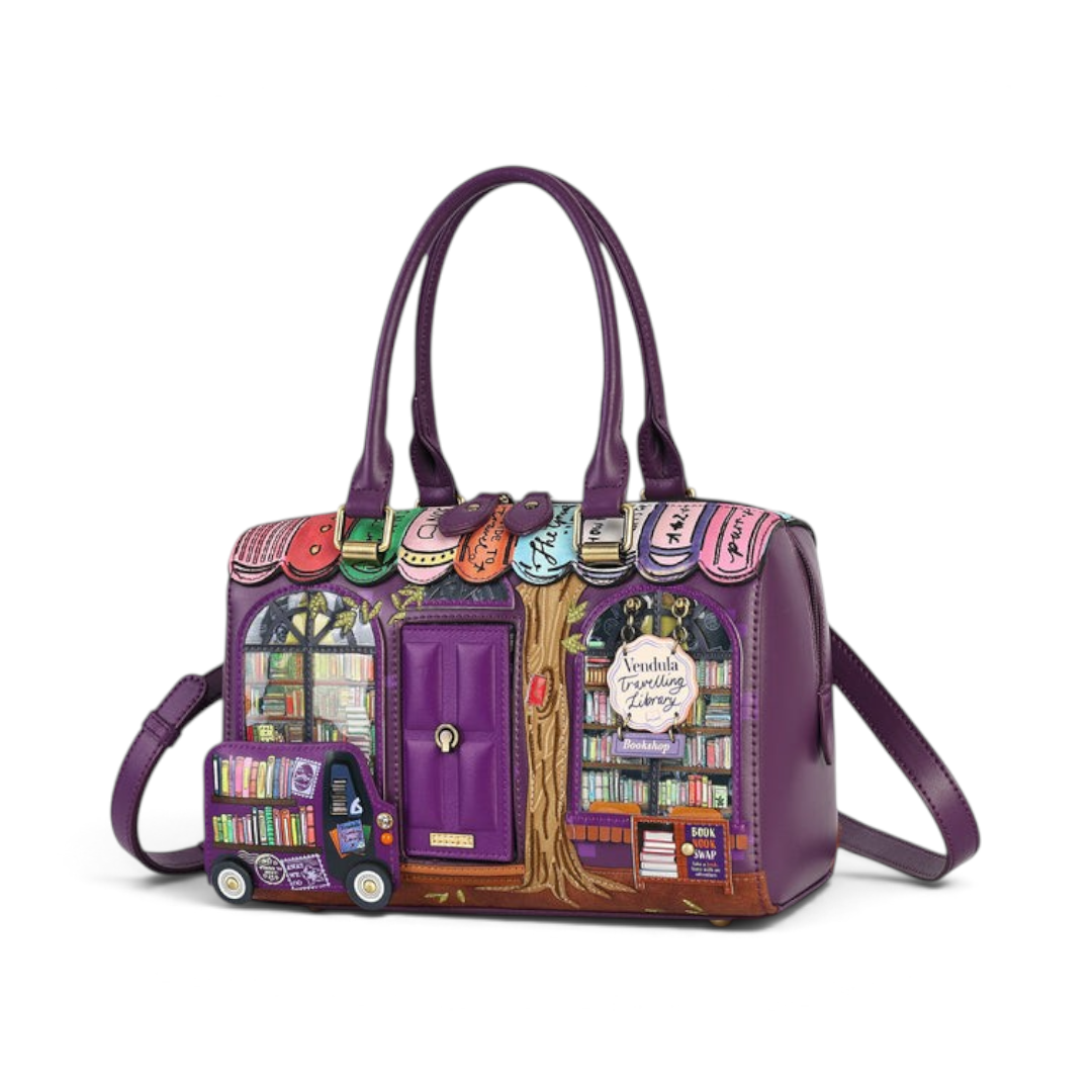 The Happy Shoe Shop Vendula London purple vegan leather bowler bag featuring a detailed bookshop scene and handles.