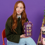 The Happy Shoe Shop Vendula London purple telephone box novelty bag held by a woman against a purple background.