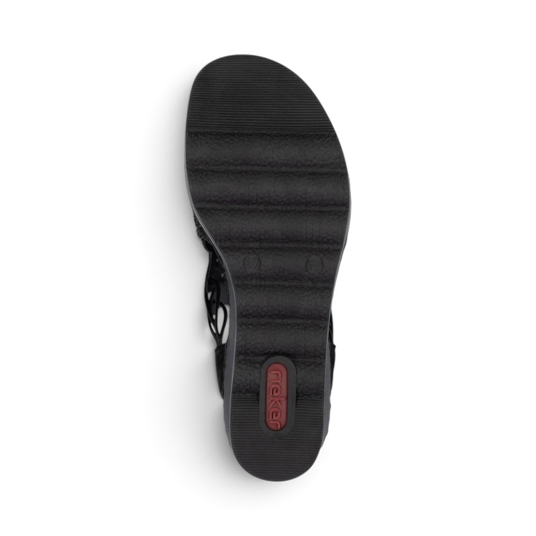 The Happy Shoe Shop Rieker 67465 wedge sandal showing the black textured Riricon outsole from a bottom view.