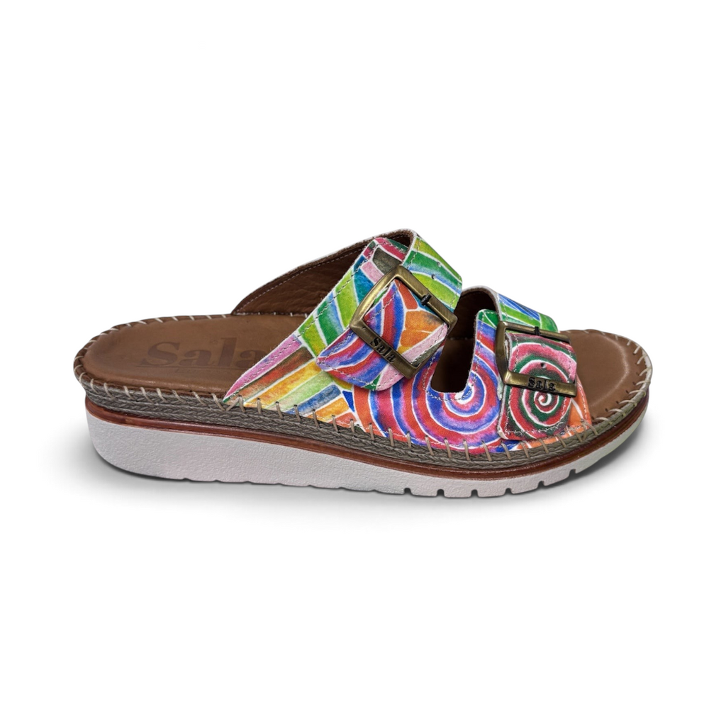 The Happy Shoe Shop Sala Oasis leather wedge slides featuring a vibrant multi-colored spiral pattern and dual buckles.