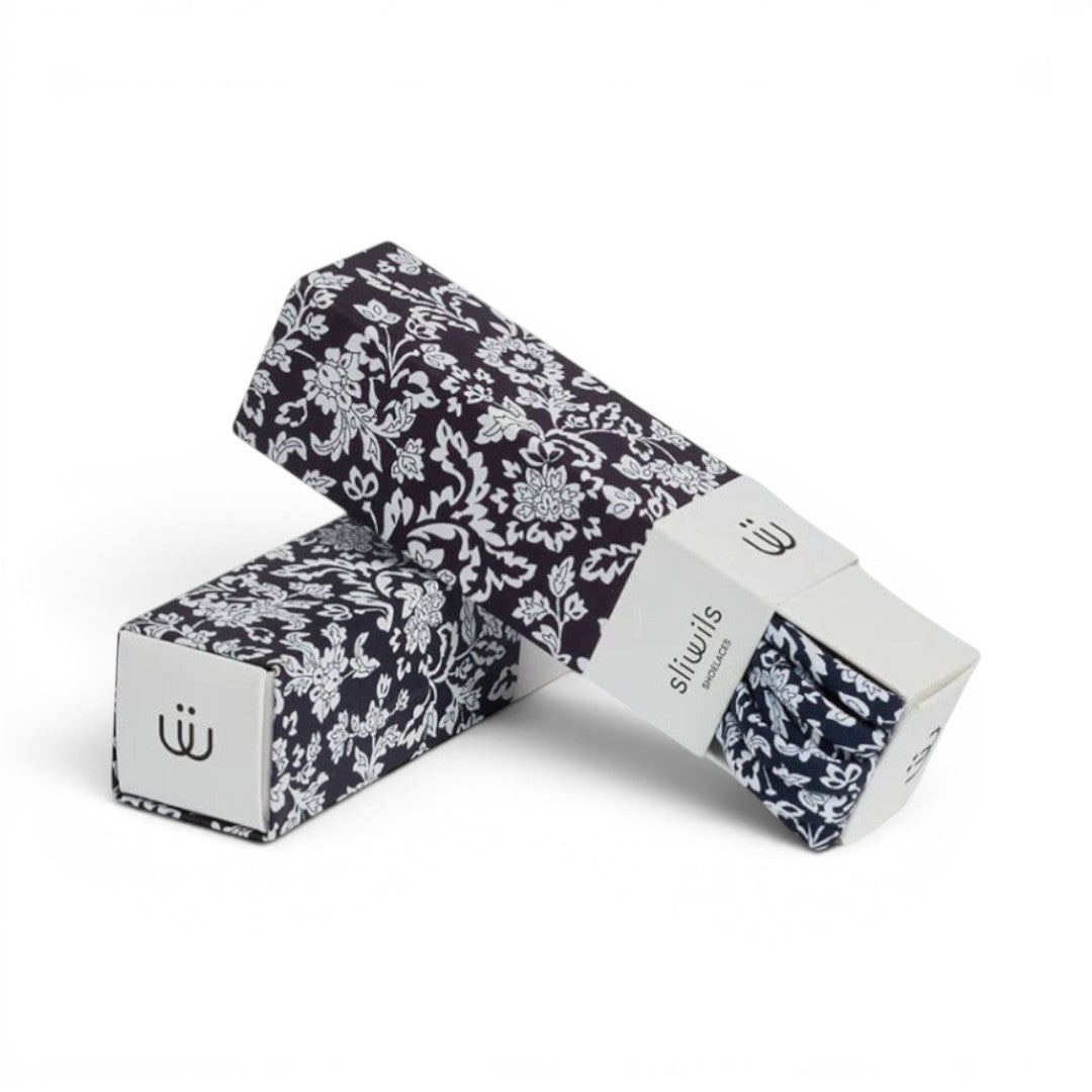 The Happy Shoe Shop Sliwils 120cm shoelaces in a black and white floral pattern, presented in premium gift packaging.