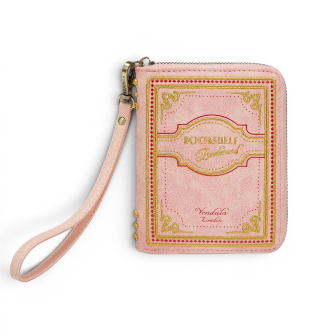 The Happy Shoe Shop Vendula London Bookshelf Boulevard Coin Purse, a pink vegan leather accessory designed like a book with gold embossed details and a wrist strap.