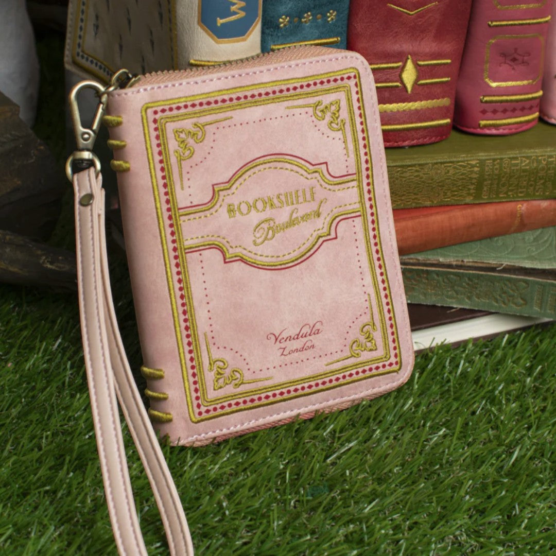 The Happy Shoe Shop Vendula London Bookshelf Boulevard coin purse is pink vegan leather designed like a book with gold trim and text.