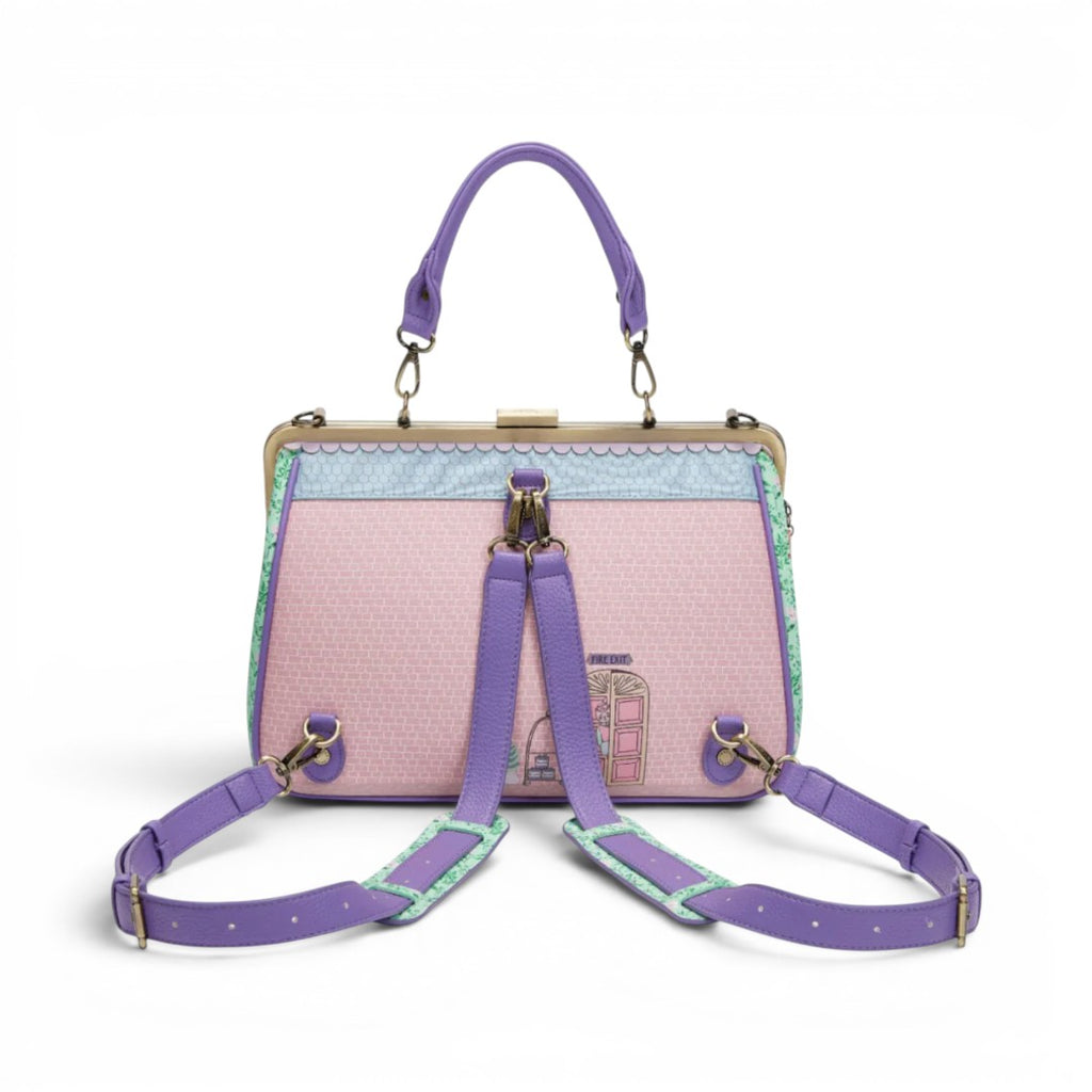 The Happy Shoe Shop Grand Vendula Hotel Willow Clip Frame Bag in pink vegan leather with purple straps and hotel design.