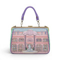 The Happy Shoe Shop Grand Vendula Hotel Willow Clip Frame Bag, pink vegan leather with hotel facade, purple handle, antique gold hardware.