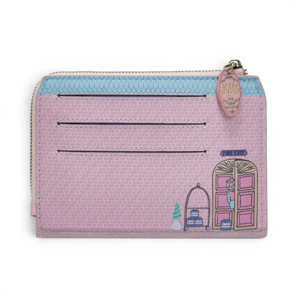 The Happy Shoe Shop Grand Vendula Hotel coin purse is pink vegan leather with a brick pattern, card slots, and a hotel door graphic. It has a zip closure and keychain.