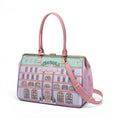 The Happy Shoe Shop Grand Vendula Hotel Sylvie Clip Frame Holdall Bag with pink handles and strap, featuring a hotel facade print.