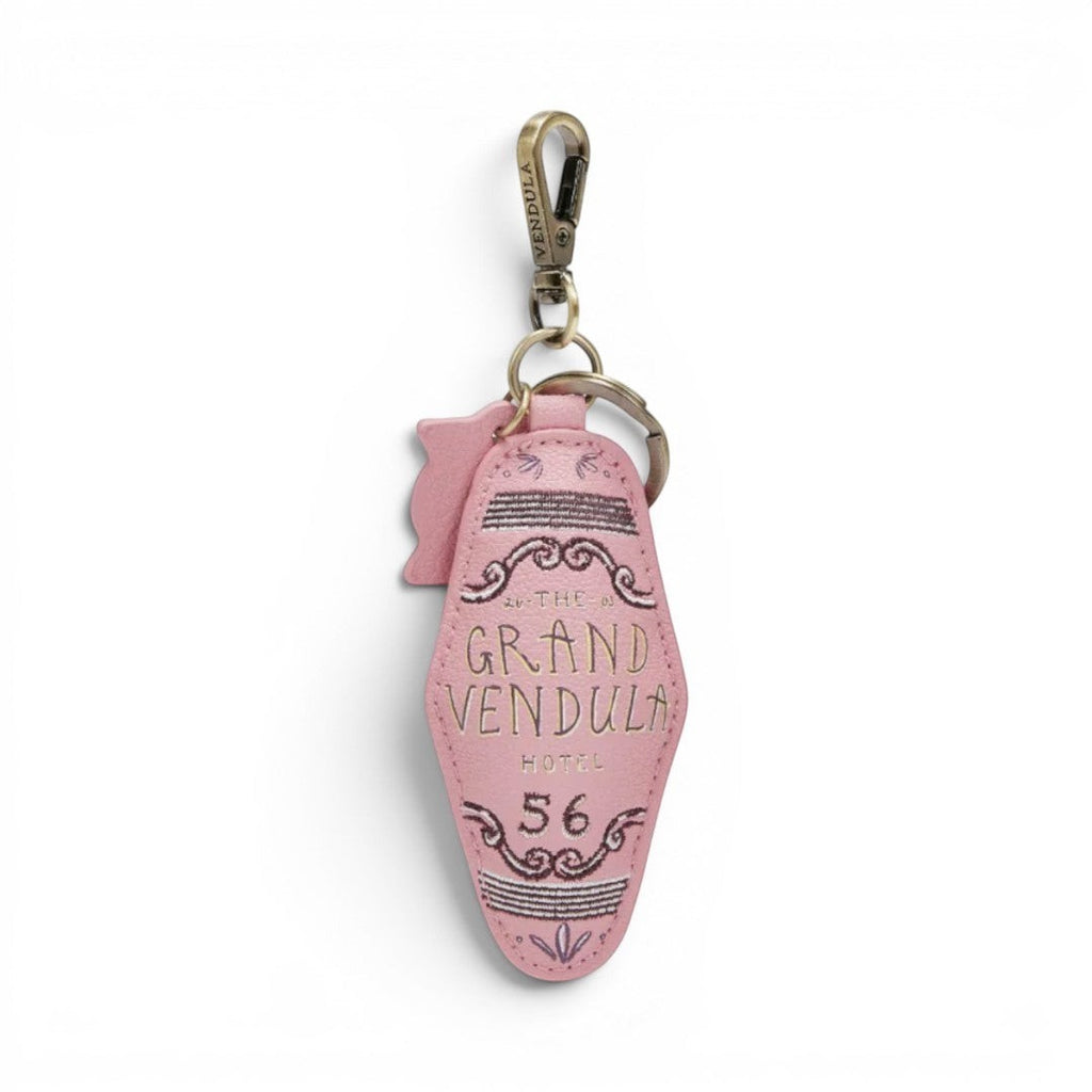 The Grand Vendula Hotel Key Charm by The Happy Shoe Shop, a pink vegan leather keychain with embossed lettering and antique gold hardware.