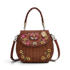 The Happy Shoe Shop Vendula London amber wicker basket bag with floral embroidery and hedgehog appliqué details.