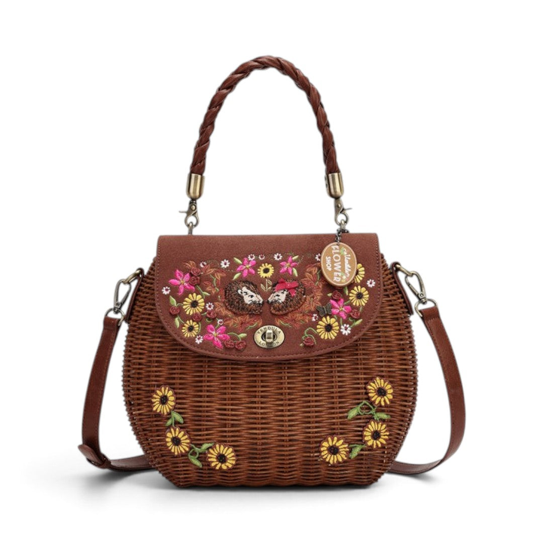 The Happy Shoe Shop Vendula London amber wicker basket bag with floral embroidery and hedgehog appliqué details.