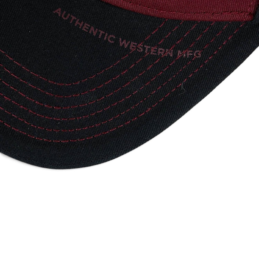 The Happy Shoe Shop Wrangler Odin trucker cap brim in black with cognac contrast stitching and embroidered text.