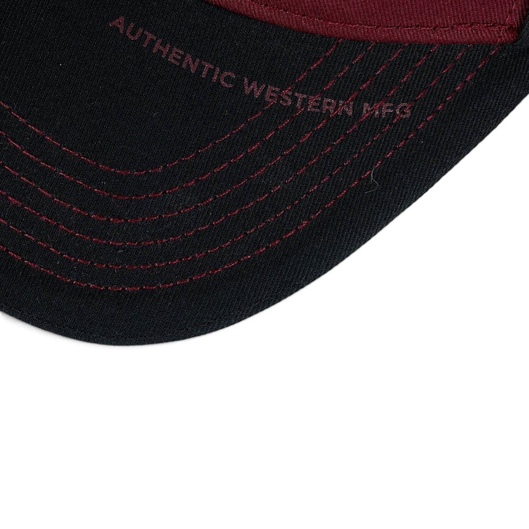 The Happy Shoe Shop Wrangler Odin trucker cap brim in black with cognac contrast stitching and embroidered text.